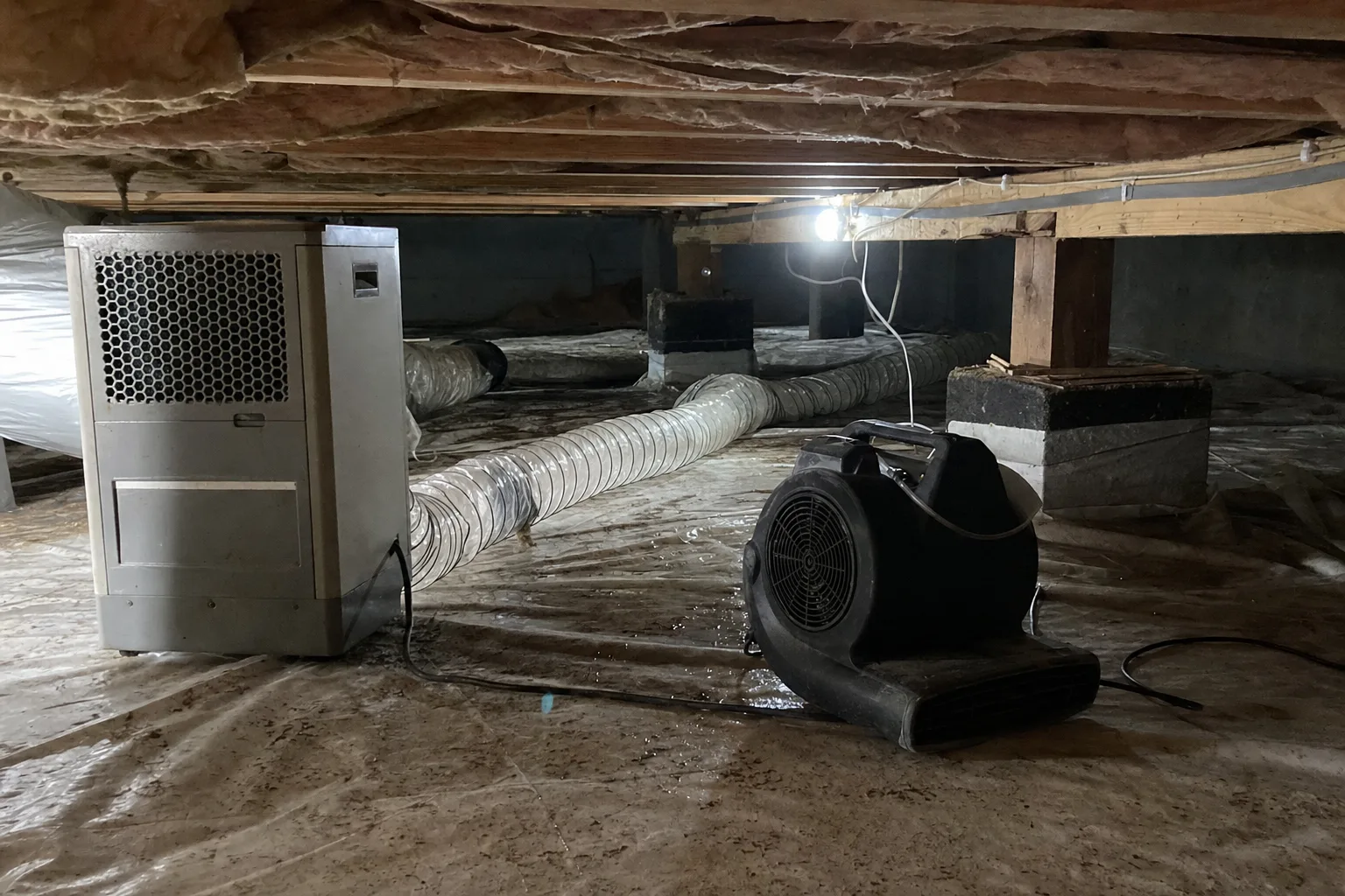 Drying equipment and dehumidification ducting staged in a residential crawl space after a water line leak