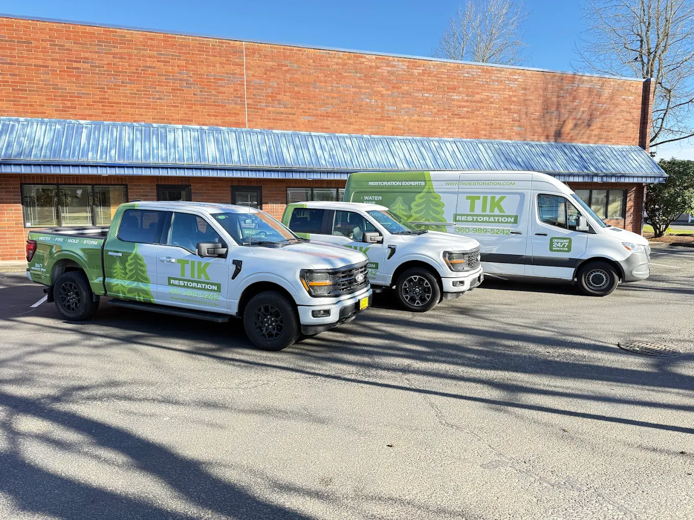 TIK Construction branded fleet — pickup trucks and box truck — at the Vancouver WA office